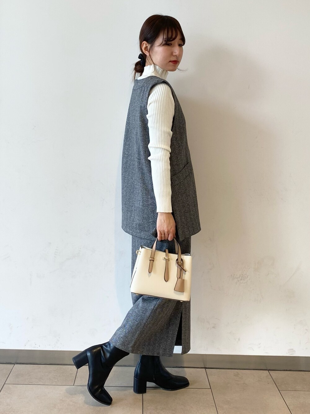 ホワイト系のニット/セーター、ブラック系のブーツ、ブラック系のベストを着用したレディースの冬コーディネートの2枚目の写真