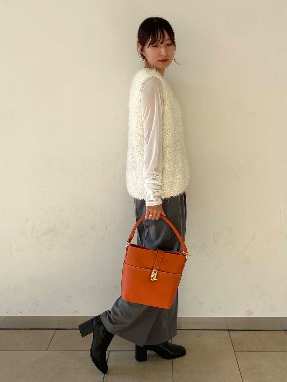 オレンジ系のハンドバッグ、グレー系のその他パンツ、ホワイト系のその他トップスを着用したレディースの秋コーディネートの2枚目の写真