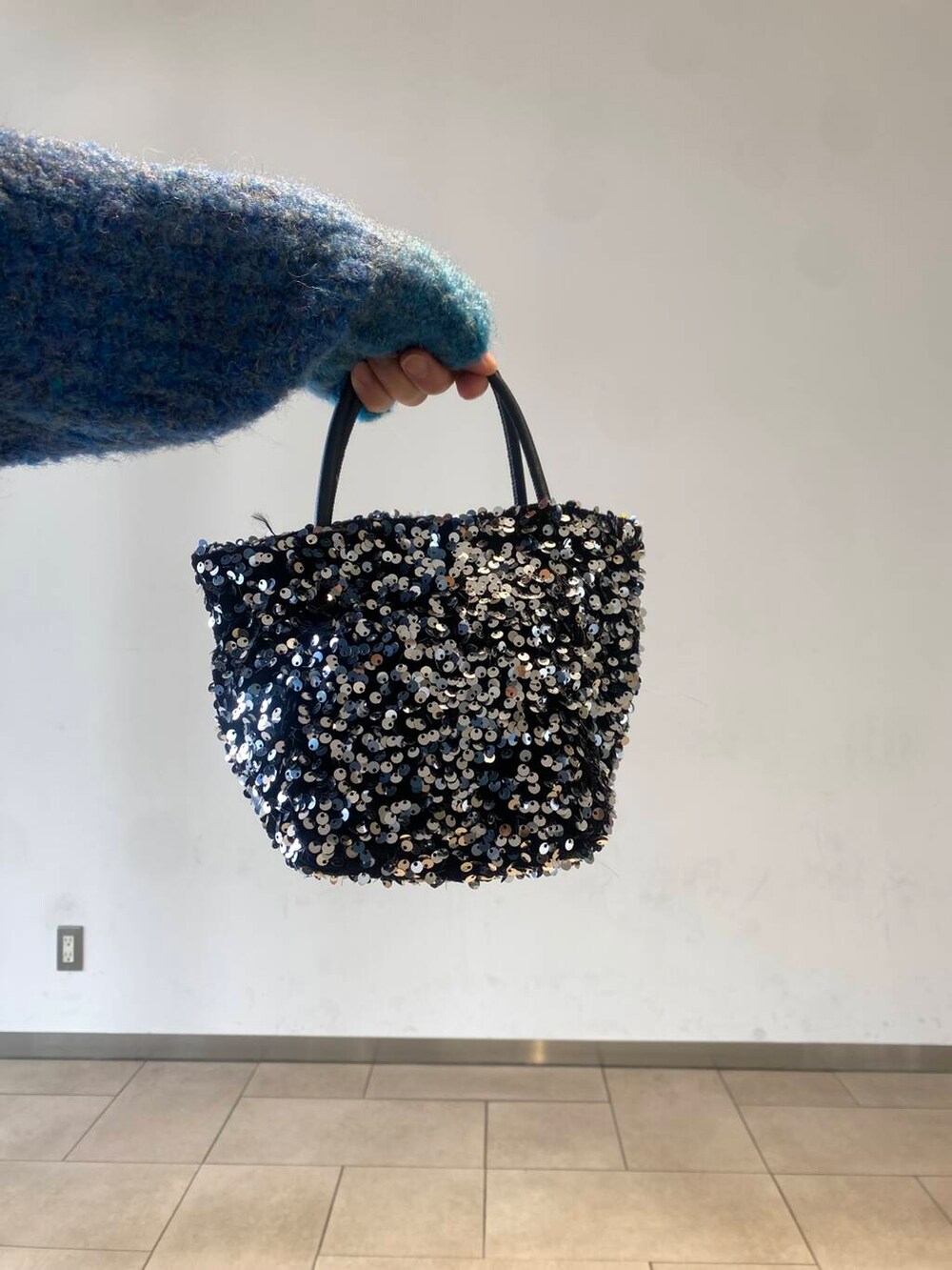 ブラック系のスカート、シルバー系のショルダーバッグ、ブラック系のブーツを着用したレディースの冬コーディネートの3枚目の写真