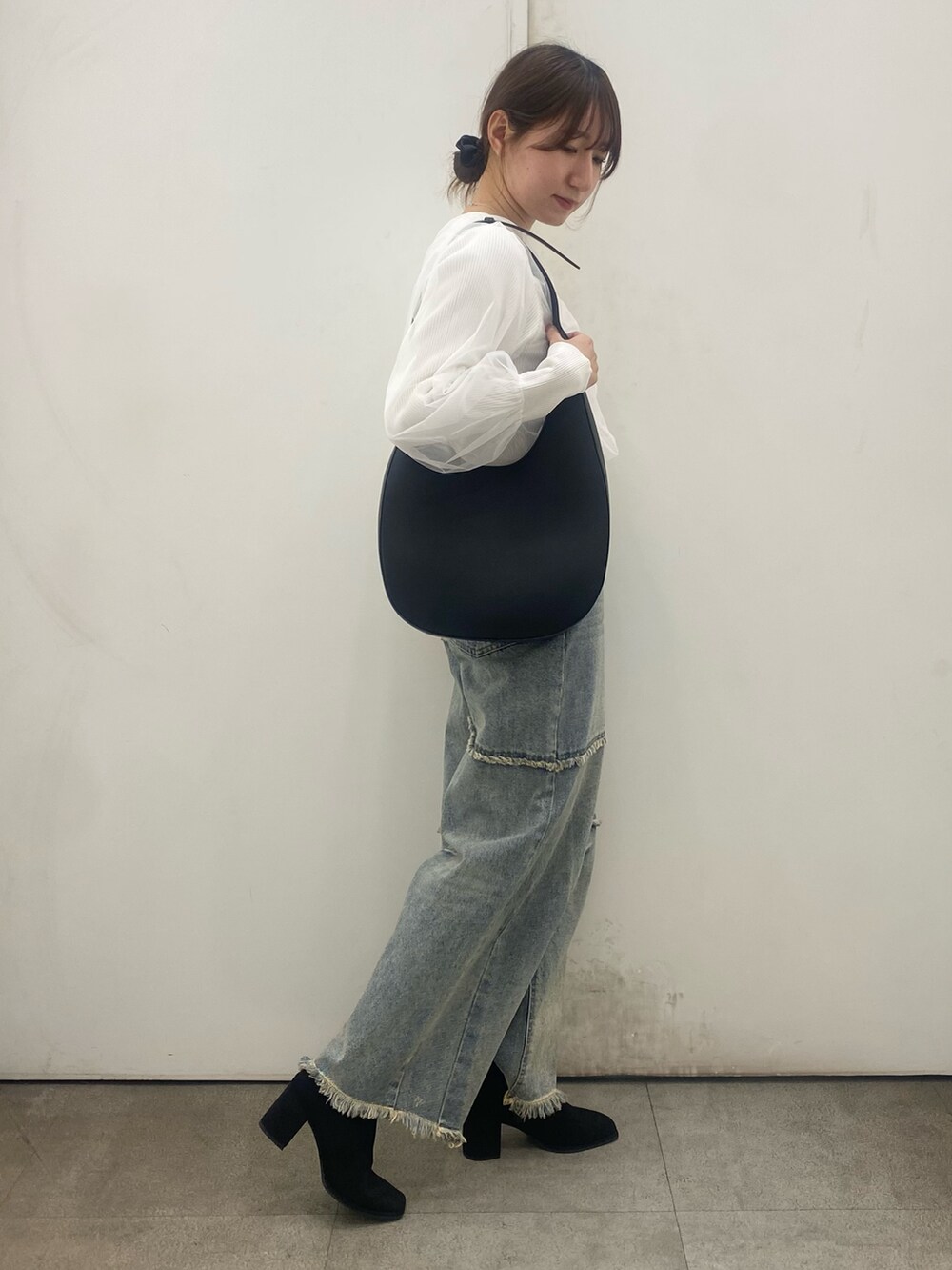 ブルー系のデニムパンツ、ホワイト系のカーディガン/ボレロ、ブラック系のブーツを着用したレディースの冬コーディネートの2枚目の写真