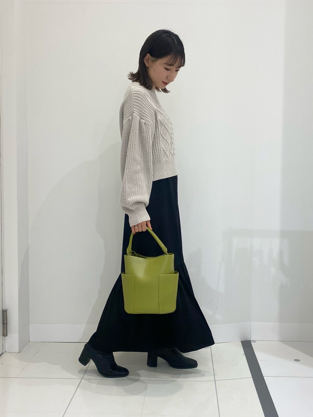 ベージュ系のワンピース、グリーン系のトートバッグ、ブラック系のブーツを着用したレディースの冬コーディネートの2枚目の写真