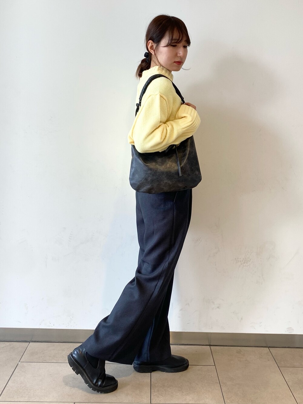 イエロー系のニット/セーター、グレー系のその他パンツ、ブラック系のブーツを着用したレディースの冬コーディネートの2枚目の写真