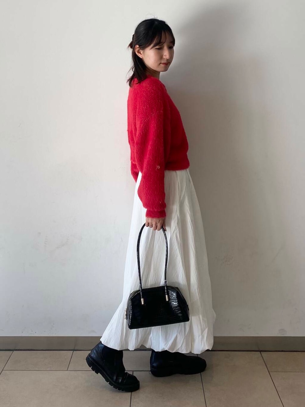 ホワイト系のスカート、ブラック系のブーツ、ブラック系のハンドバッグを着用したレディースの冬コーディネートの3枚目の写真