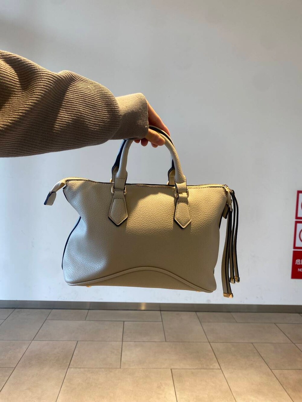 ホワイト系のボストンバッグ、ブラック系のブーツ、ベージュ系のニット/セーターを着用したレディースの冬コーディネートの3枚目の写真