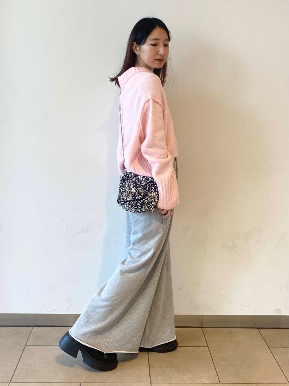 シルバー系のショルダーバッグ、ブラック系のブーツ、グレー系のスウェットパンツを着用したレディースの冬コーディネートの2枚目の写真