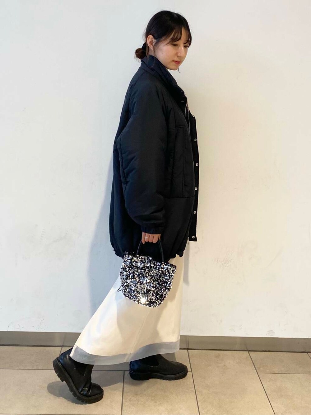 ブラック系のブーツ、グレー系のニット/セーター、ホワイト系のスカートを着用したレディースの冬コーディネートの4枚目の写真