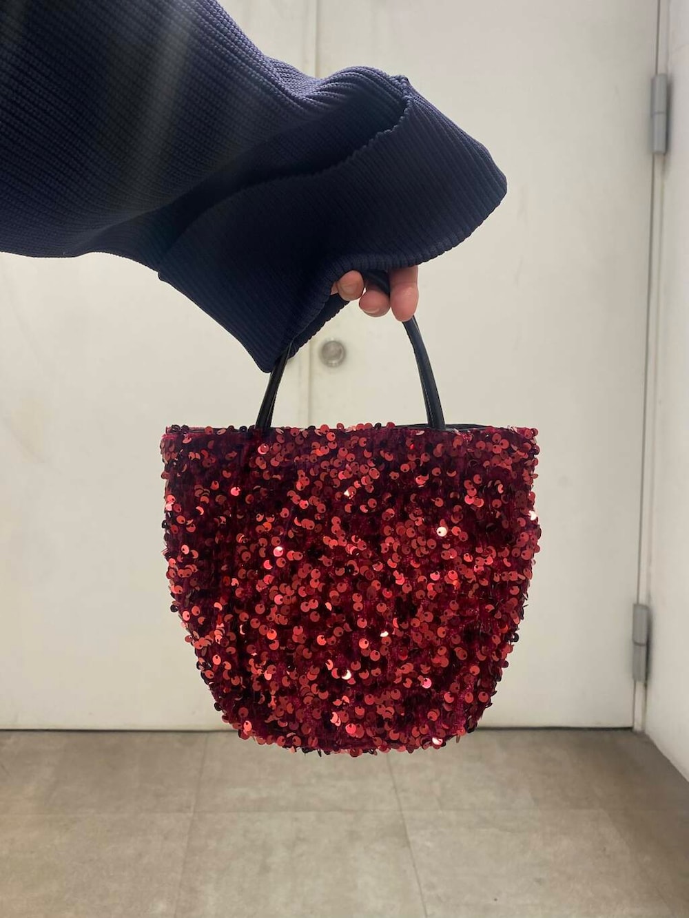 ブラック系のブーツ、レッド系のショルダーバッグ、ホワイト系のスカートを着用したレディースの冬コーディネートの3枚目の写真