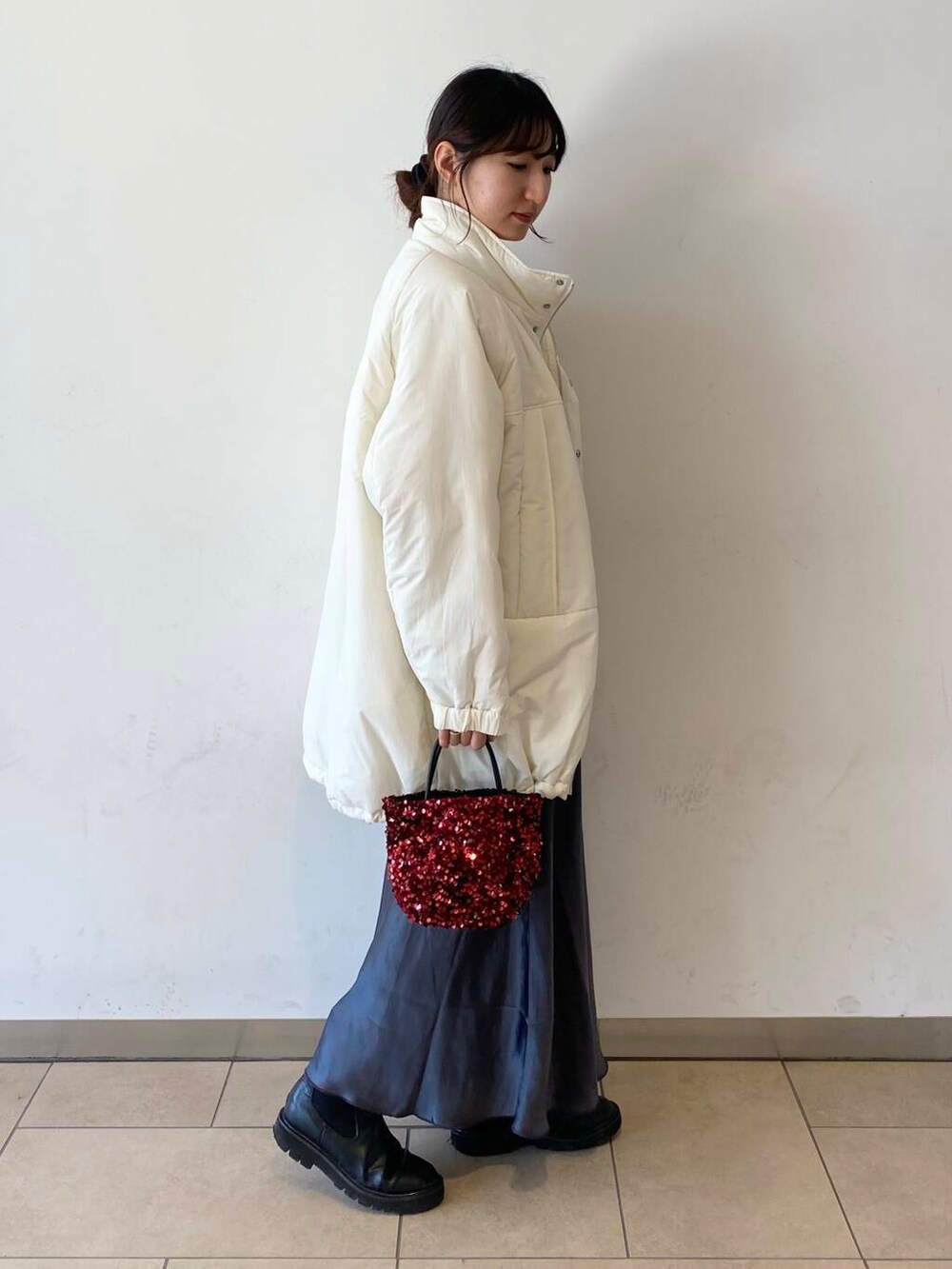 ベージュ系のニット/セーター、ブラック系のブーツ、グレー系のスカートを着用したレディースの秋コーディネートの2枚目の写真