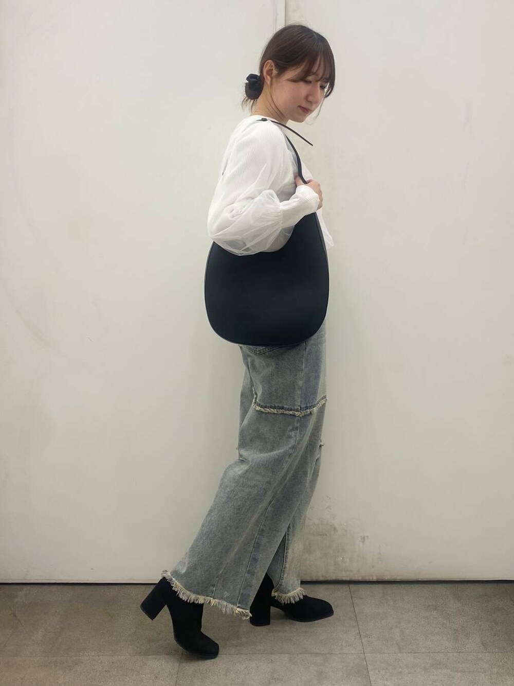 ブラック系のブーツ、ブラック系のショルダーバッグ、ブルー系のデニムパンツを着用したレディースの冬コーディネートの2枚目の写真