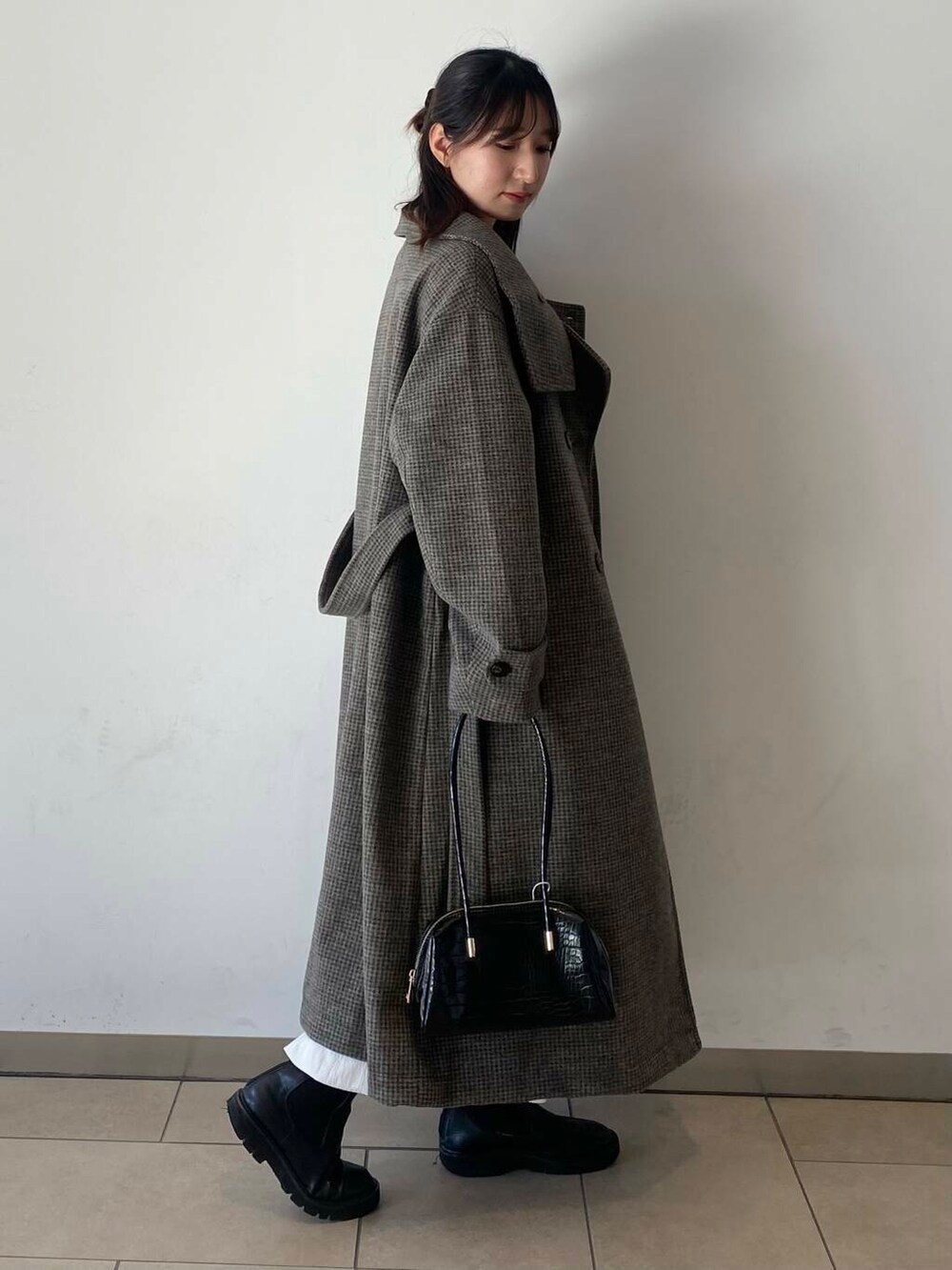 ホワイト系のスカート、ブラック系のブーツ、ブラック系のハンドバッグを着用したレディースの冬コーディネートの4枚目の写真