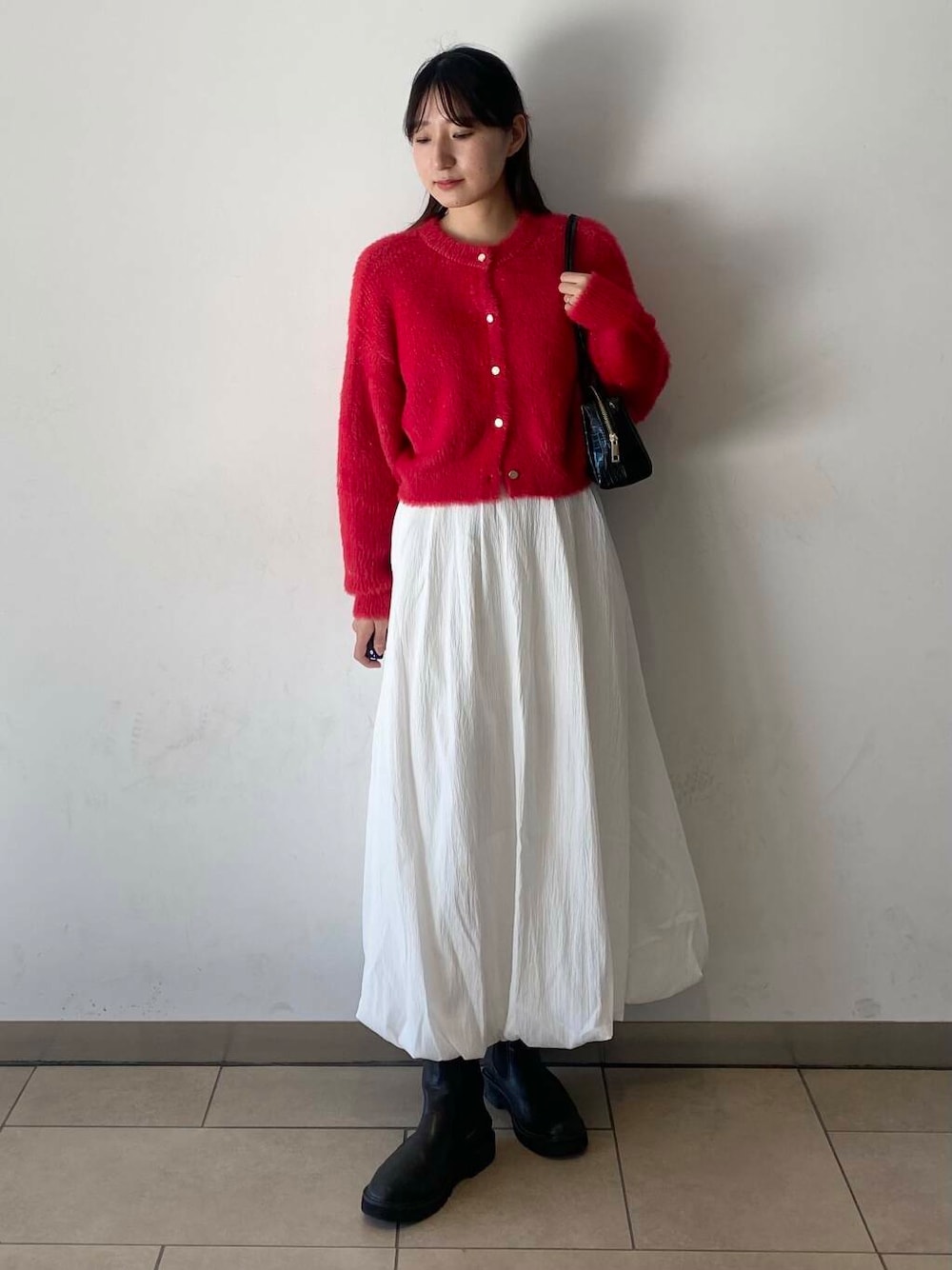 ホワイト系のスカート、ブラック系のブーツ、ブラック系のハンドバッグを着用したレディースの冬コーディネートの2枚目の写真