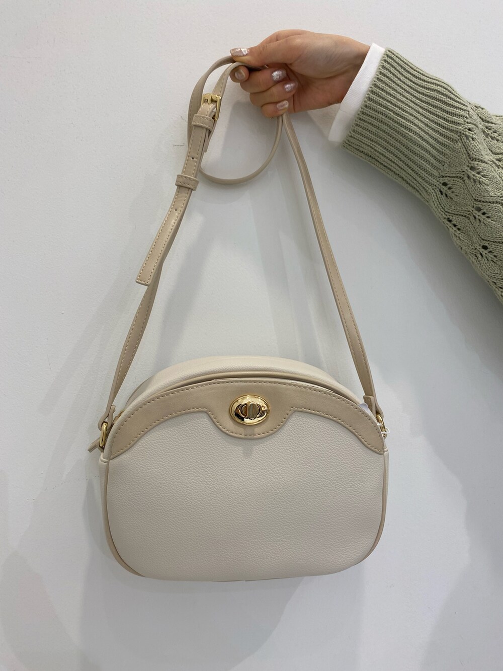 グリーン系のニット/セーター、ホワイト系のショルダーバッグ、ホワイト系のTシャツ/カットソーを着用したレディースの冬コーディネートの3枚目の写真