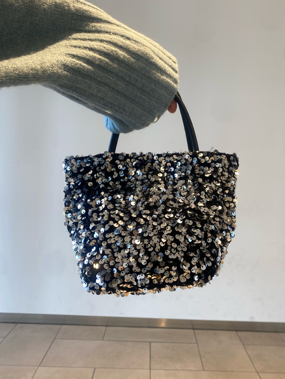 ホワイト系のスカート、ブルー系のニット/セーター、ブラック系のブーツを着用したレディースの冬コーディネートの3枚目の写真