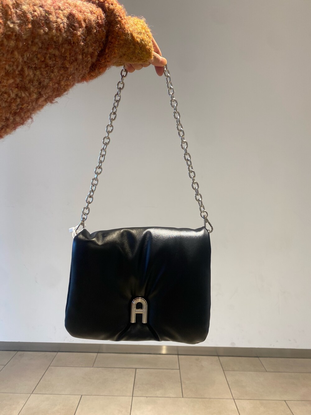 ホワイト系のスカート、オレンジ系のニット/セーター、ブラック系のブーツを着用したレディースの秋コーディネートの3枚目の写真