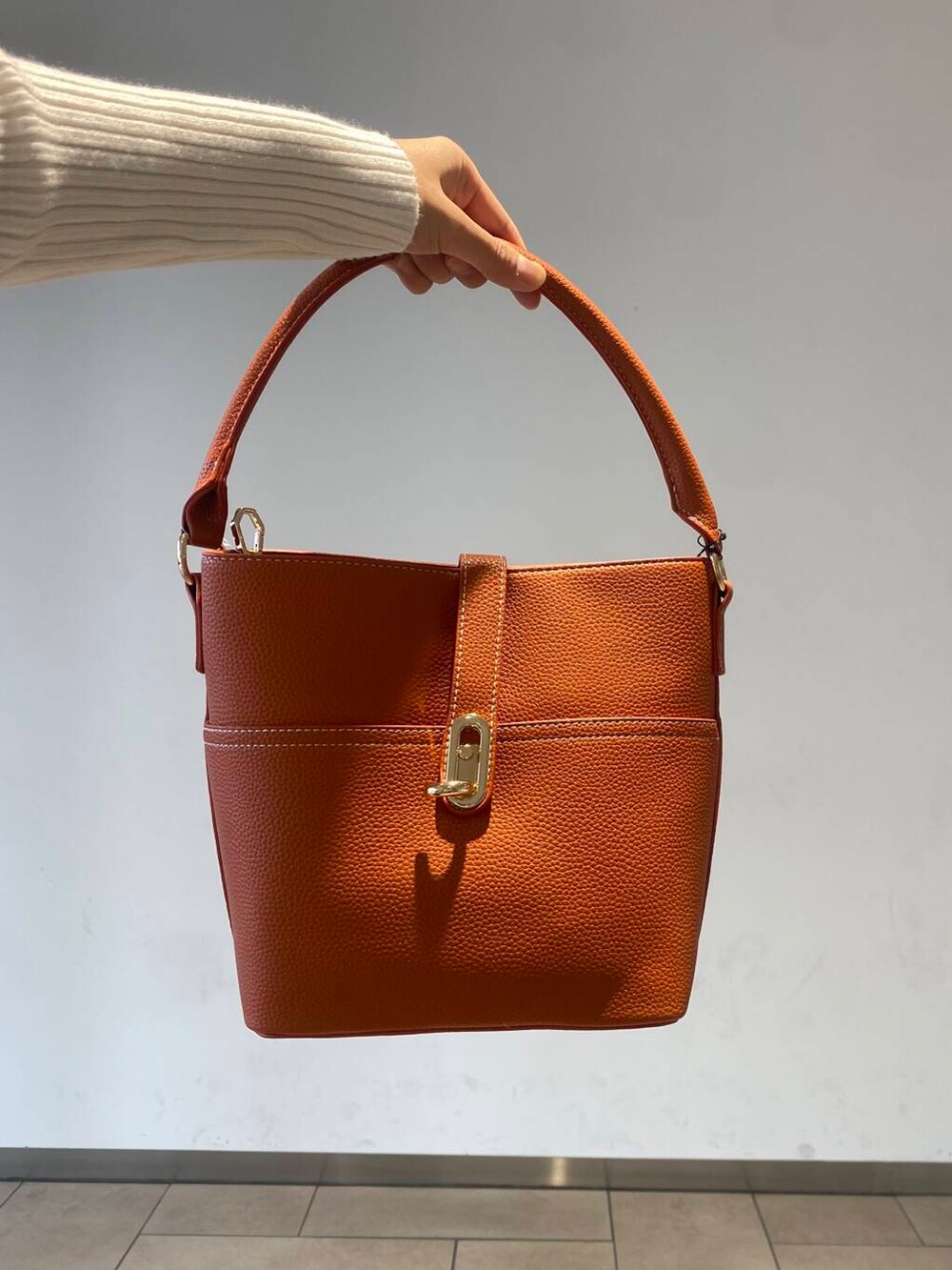 ホワイト系のニット/セーター、オレンジ系のハンドバッグ、ブラック系のブーツを着用したレディースの秋コーディネートの3枚目の写真