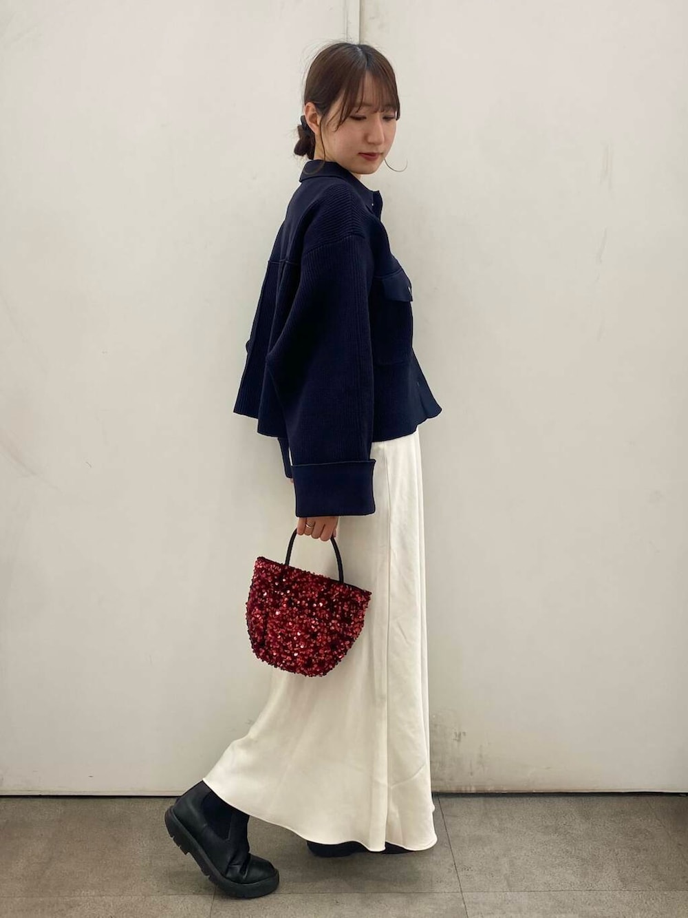 ブラック系のブーツ、レッド系のショルダーバッグ、ホワイト系のスカートを着用したレディースの冬コーディネートの2枚目の写真