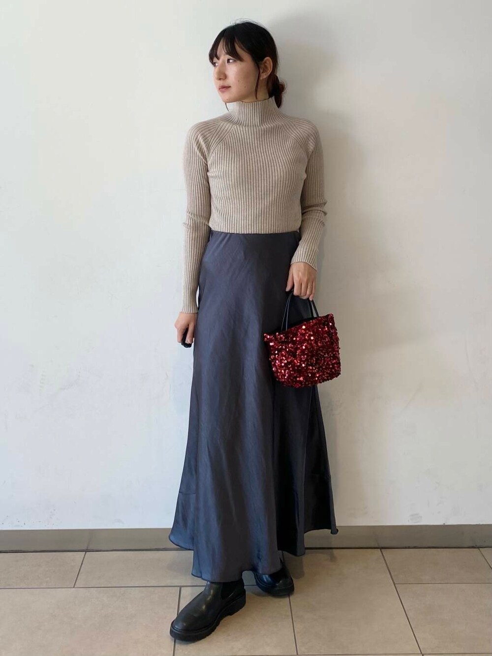 ベージュ系のニット/セーター、ブラック系のブーツ、グレー系のスカートを着用したレディースの秋コーディネートの3枚目の写真