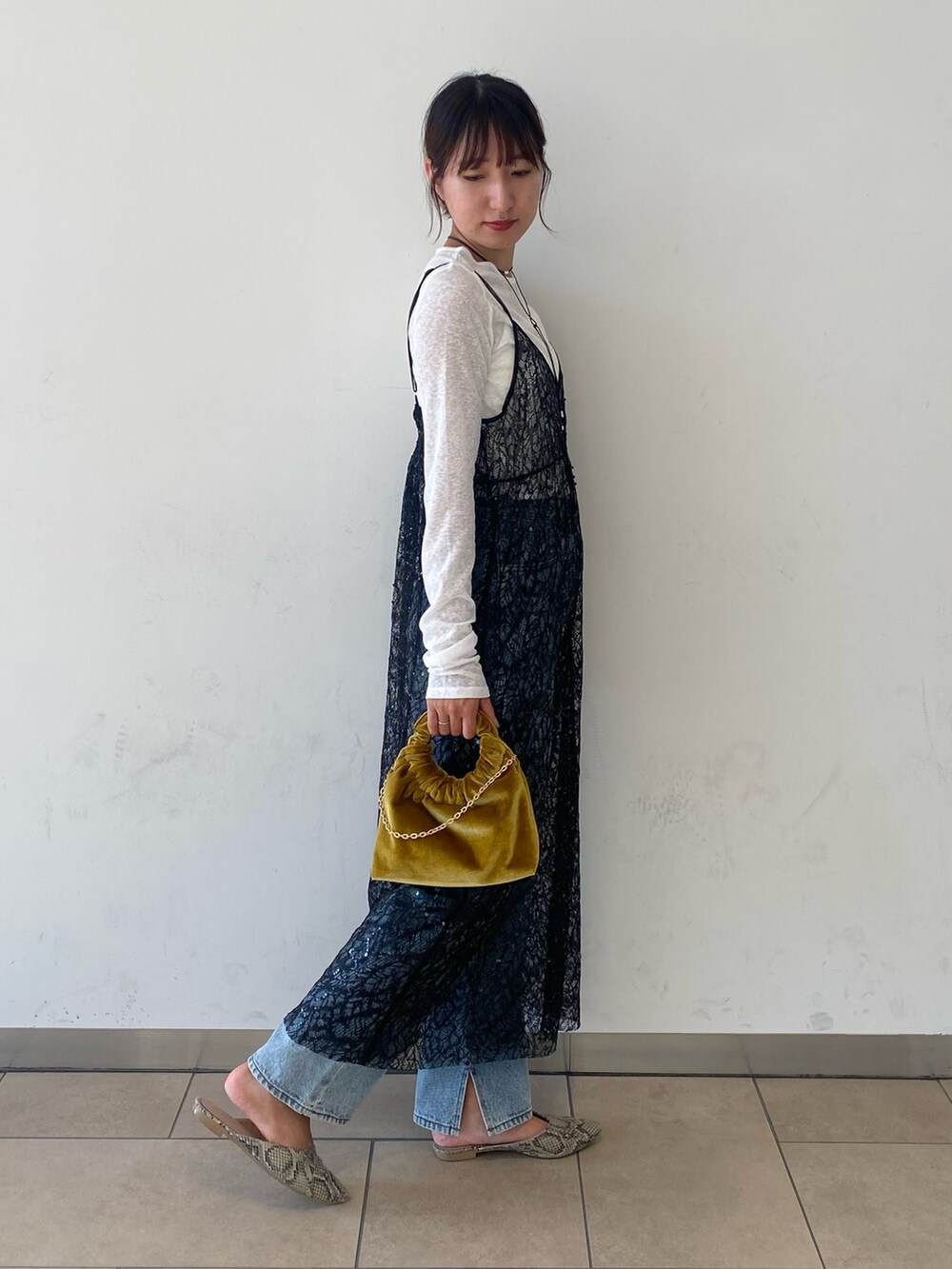 ブラック系のワンピース、イエロー系のハンドバッグ、ブルー系のデニムパンツを着用したレディースの秋コーディネートの2枚目の写真