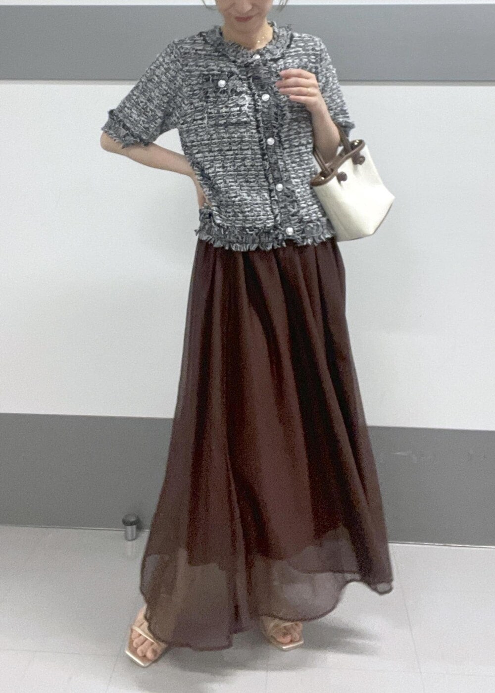 ゴールド系のサンダル、ブラウン系のトートバッグ、ブラウン系のスカートを着用したレディースの夏コーディネートの4枚目の写真