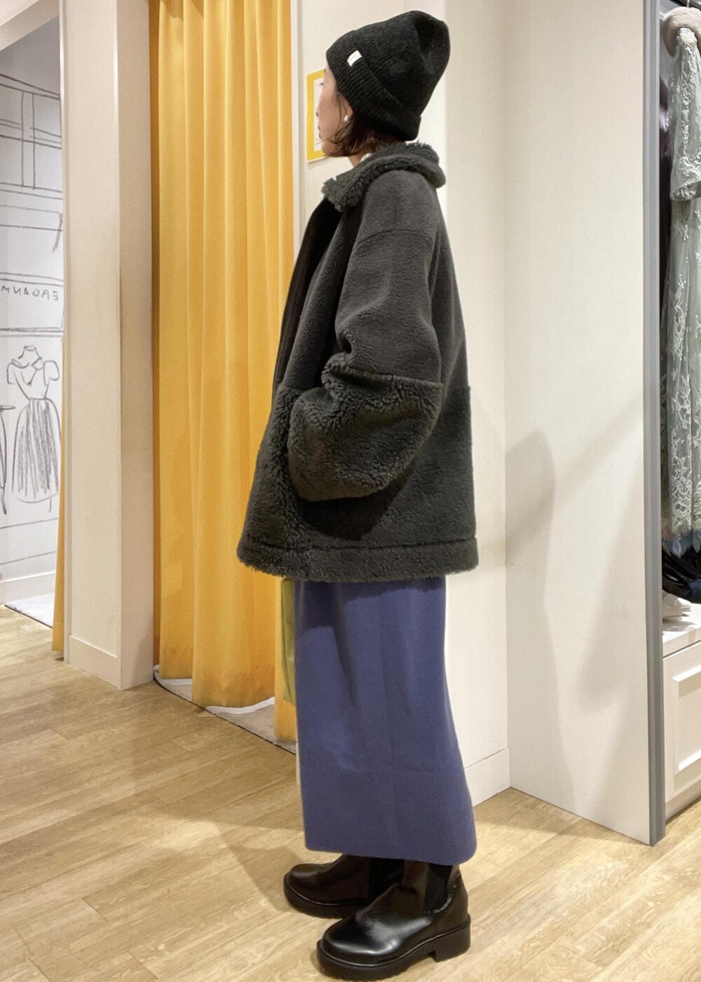 ブルー系のジャンパースカート、ホワイト系のニット/セーター、グレー系のブルゾンを着用したレディースの冬コーディネートの3枚目の写真