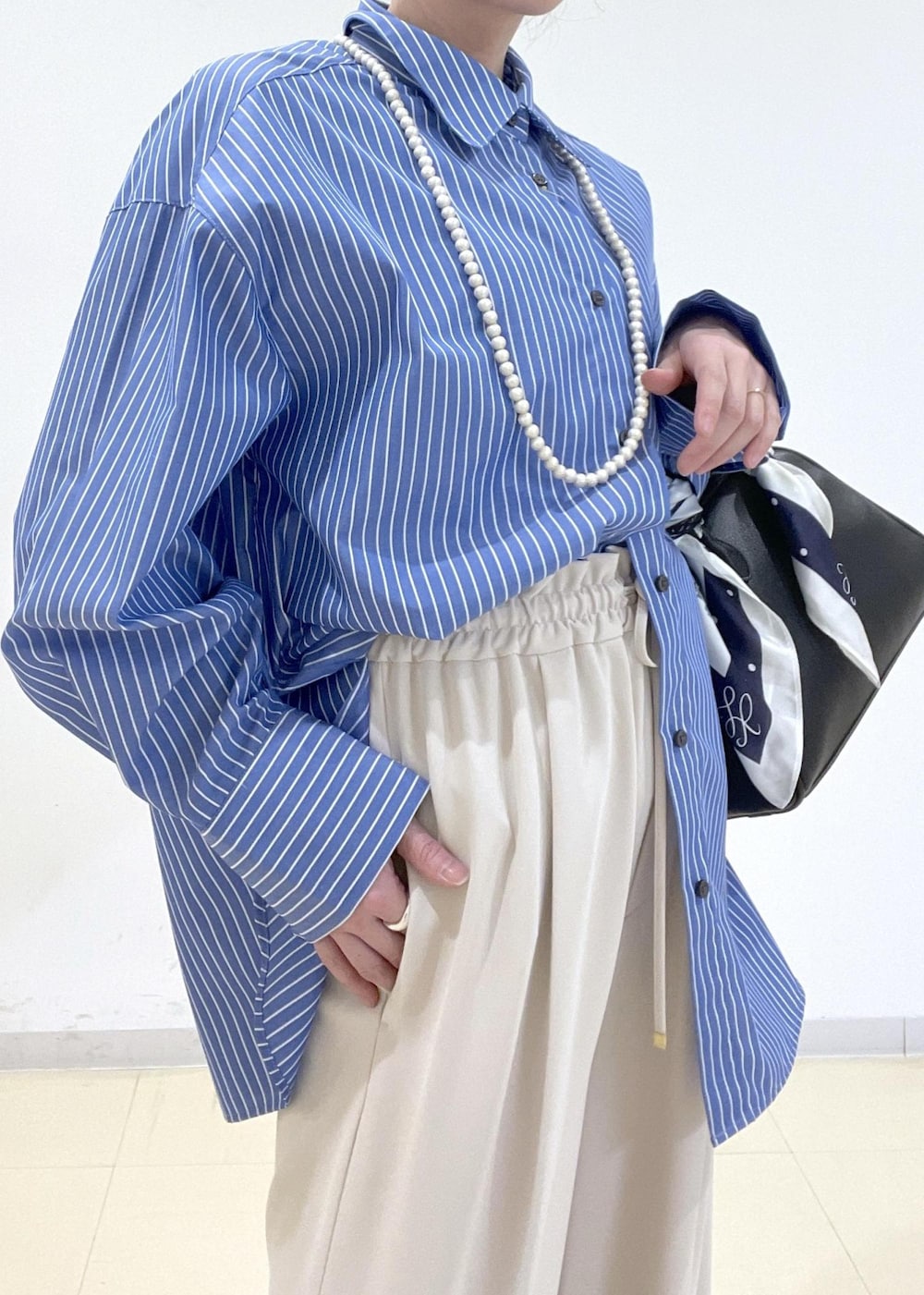 ブルー系のシャツ/ブラウス、ブラック系のボストンバッグ、ベージュ系のその他パンツを着用したレディースの春コーディネートの2枚目の写真