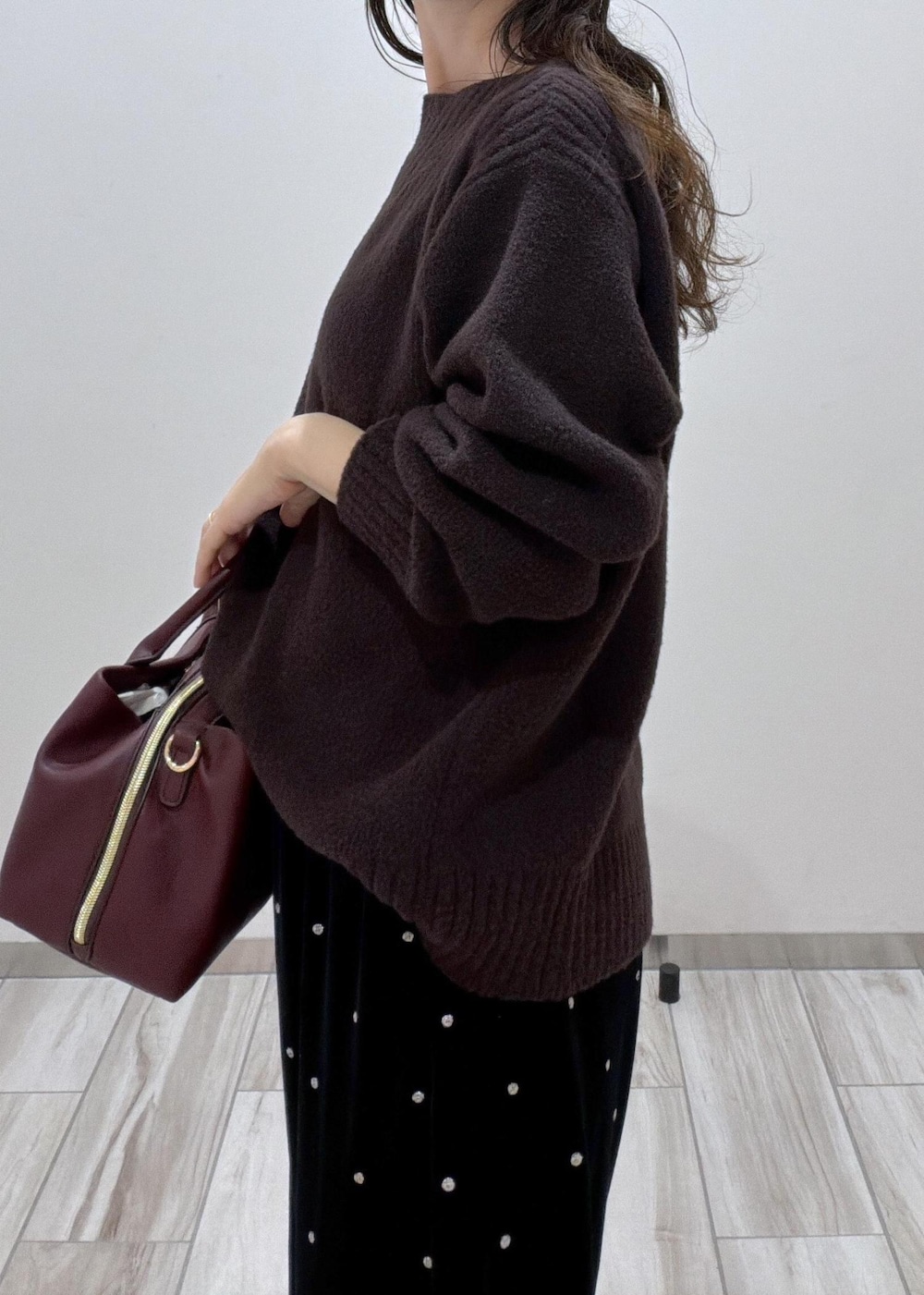 レッド系のトートバッグ、ブラック系のパンプス、ブラウン系のニット/セーターを着用したレディースの秋コーディネートの5枚目の写真