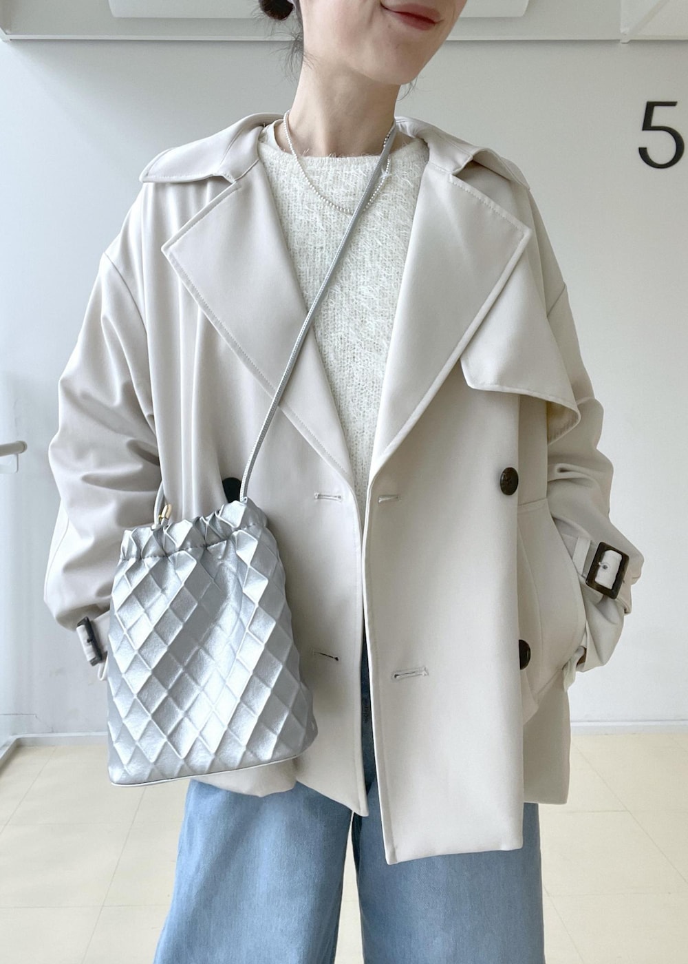 ベージュ系のトレンチコート、ホワイト系のニット/セーター、ホワイト系のTシャツ/カットソーを着用したレディースの冬コーディネートの4枚目の写真