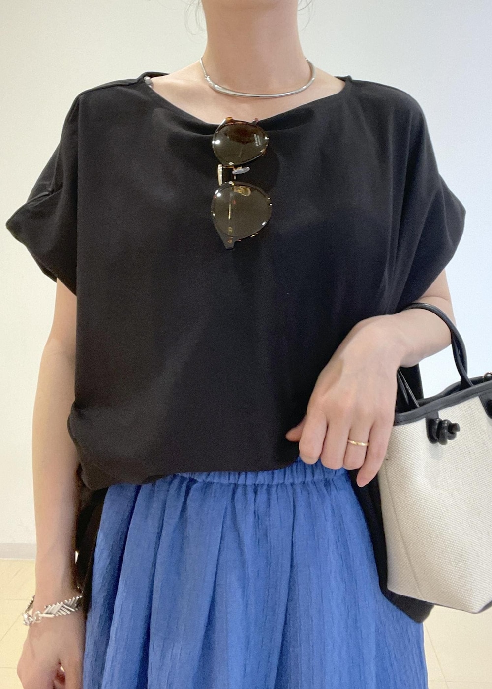 ブラック系のトートバッグ、ブルー系のスカート、グレー系のカーディガン/ボレロを着用したレディースの夏コーディネートの7枚目の写真