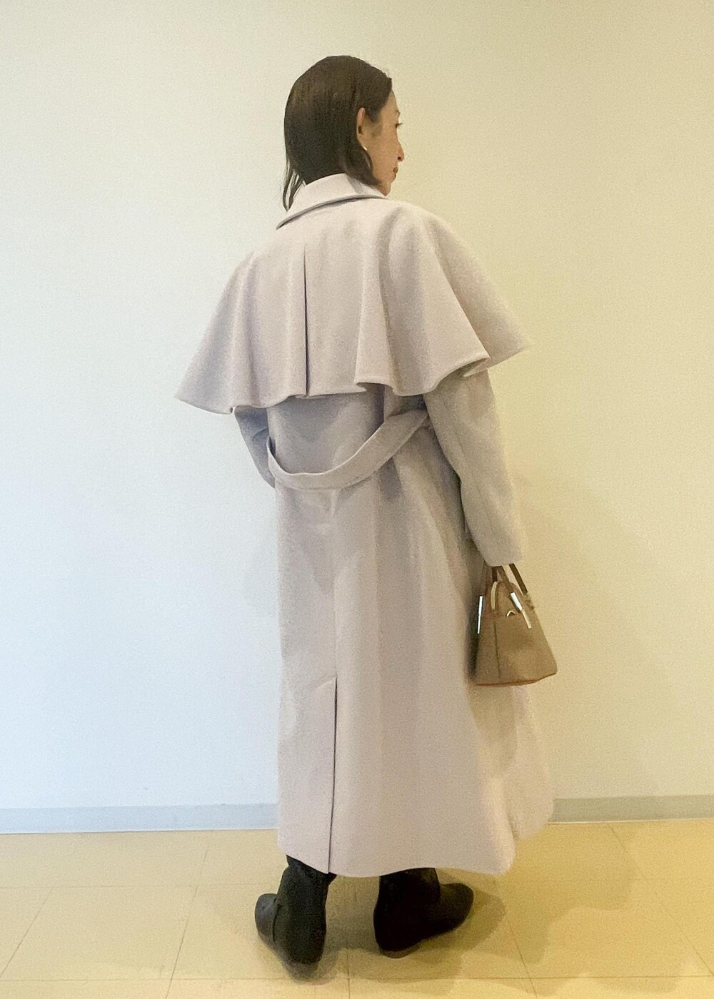 オレンジ系のカーディガン/ボレロ、ブラック系のスカート、ブラック系のブーツを着用したレディースの秋コーディネートの3枚目の写真