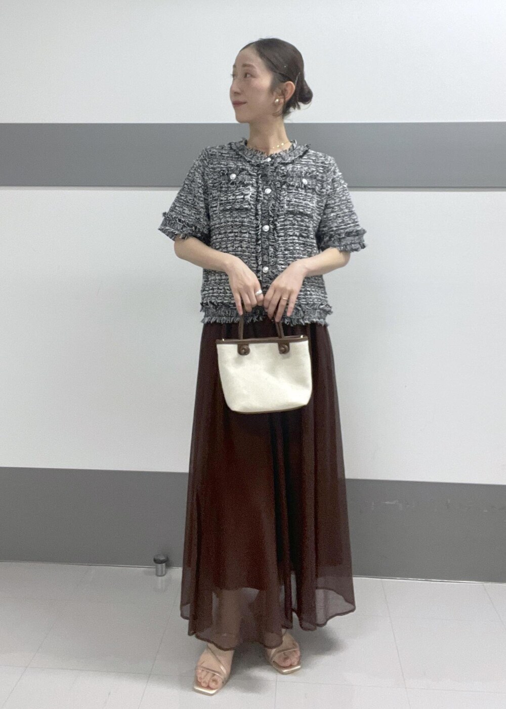 ゴールド系のサンダル、ブラウン系のトートバッグ、ブラウン系のスカートを着用したレディースの夏コーディネートの2枚目の写真