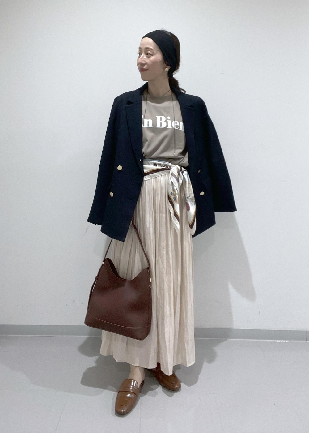 イエロー系のローファー、ベージュ系のスカート、レッド系のショルダーバッグを着用したレディースの夏コーディネートの2枚目の写真