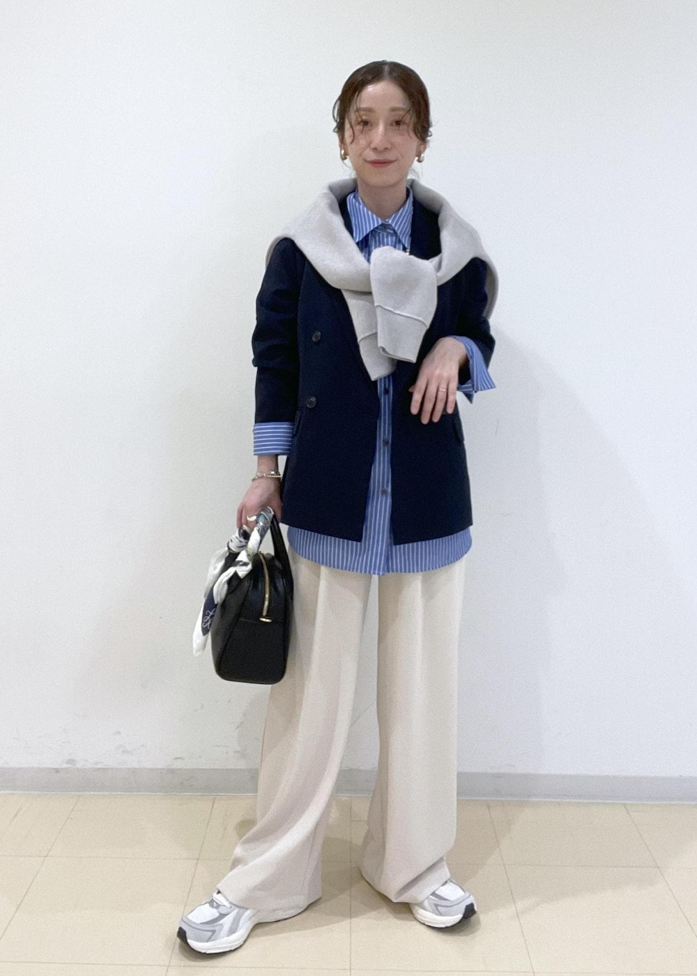 ブルー系のシャツ/ブラウス、グレー系のニット/セーター、ベージュ系のその他パンツを着用したレディースの春コーディネートの2枚目の写真