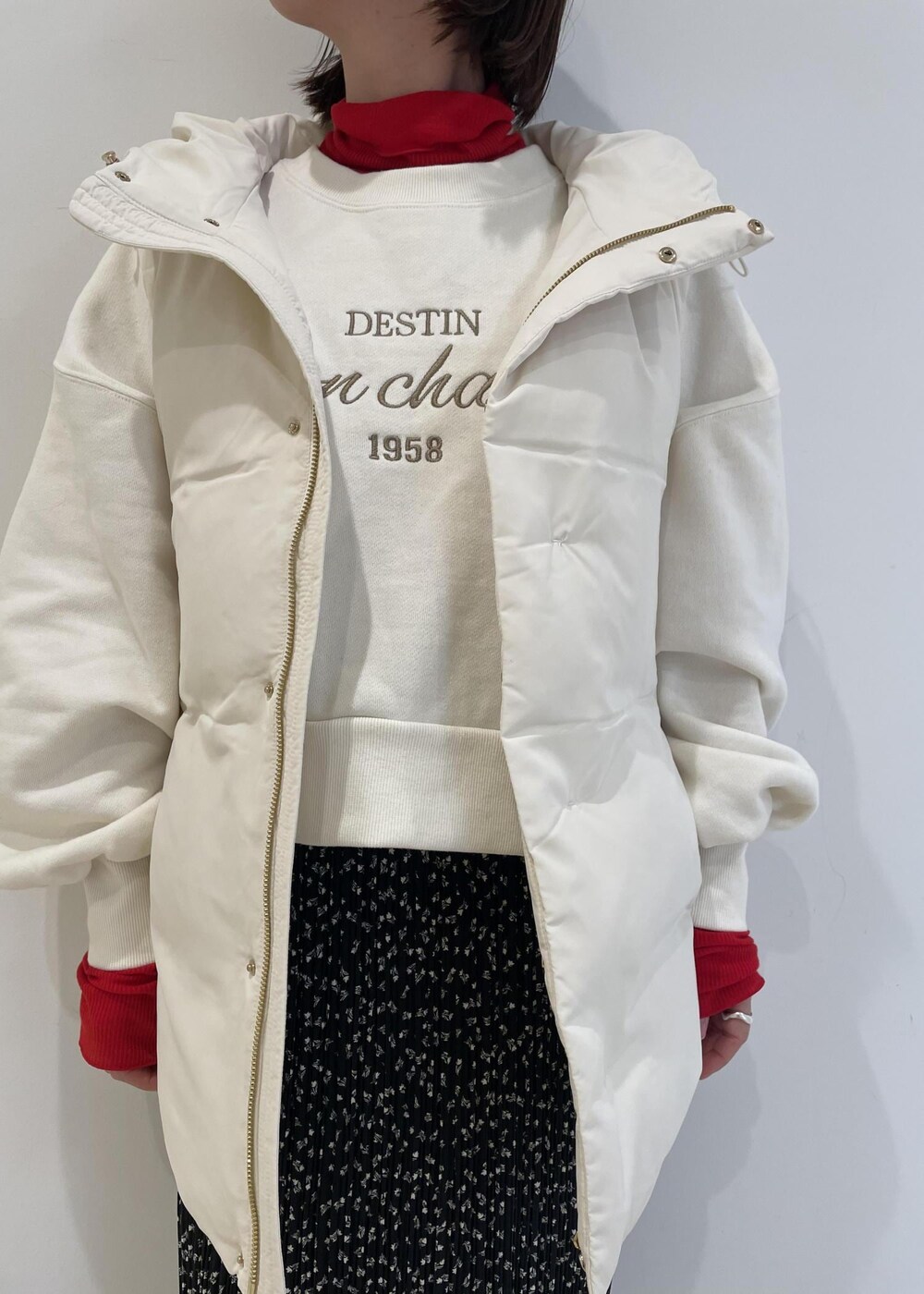 レッド系のTシャツ/カットソー、ブラック系のブーツ、ホワイト系のダウンベストを着用したレディースの冬コーディネートの2枚目の写真