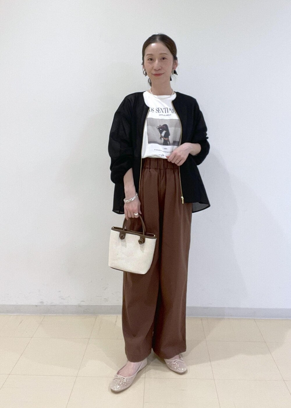 ブラック系のブルゾン、ホワイト系のバレエシューズ、ブラウン系のトートバッグを着用したレディースの春コーディネートの2枚目の写真