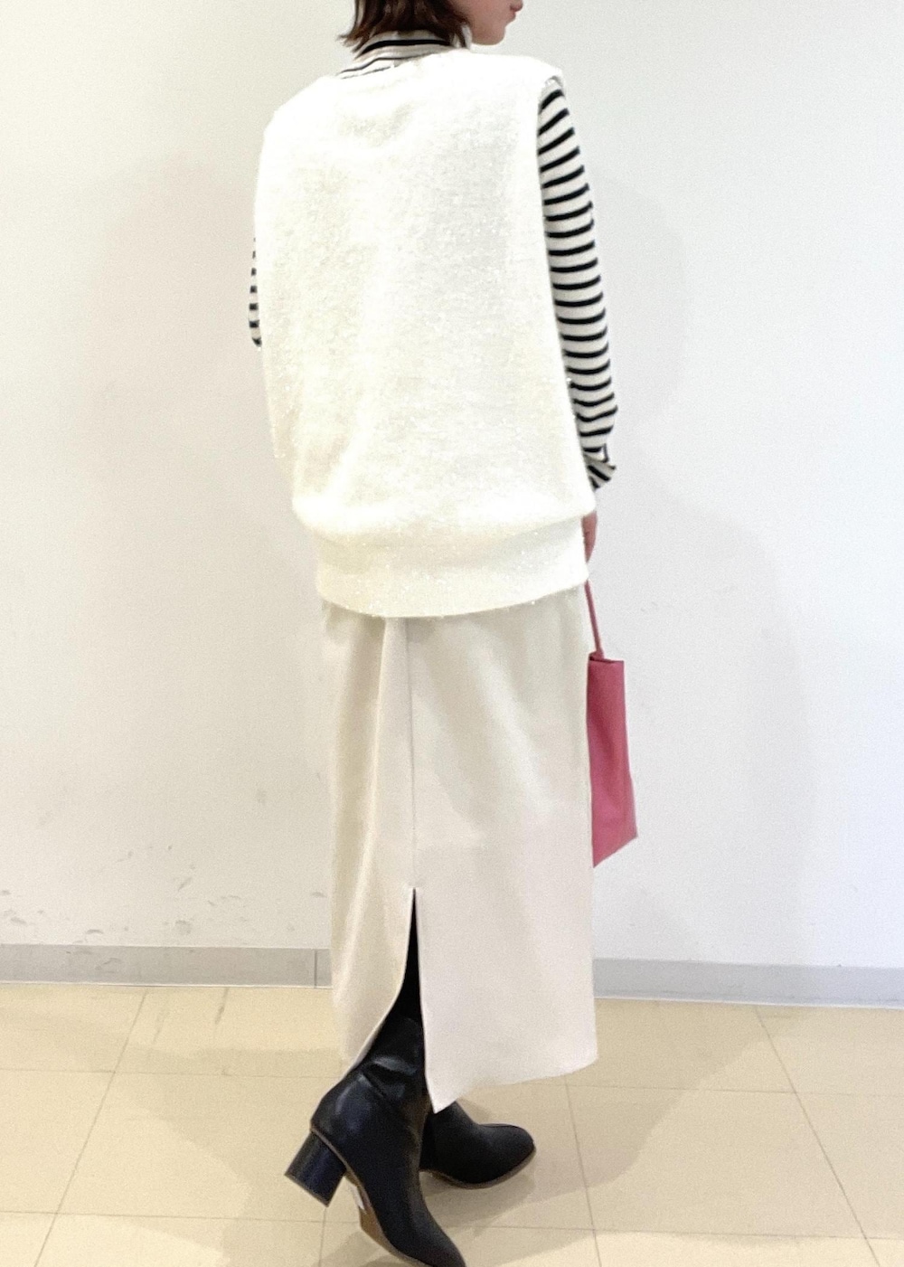 ホワイト系のワンピース、ホワイト系のニット/セーター、ブラック系のブーツを着用したレディースの冬コーディネートの2枚目の写真