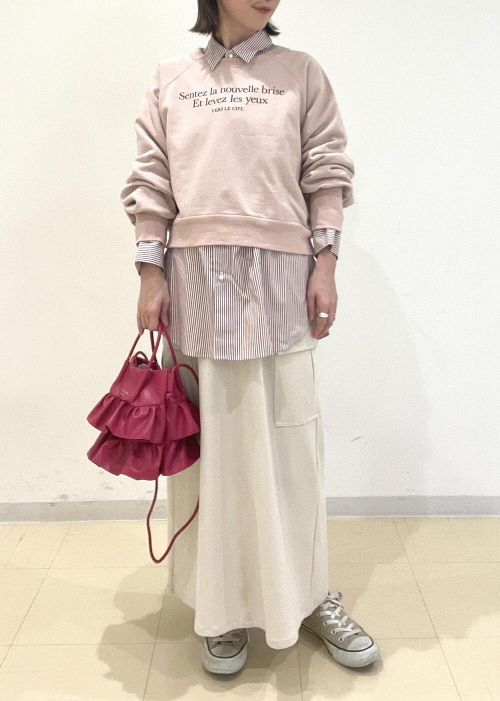 ベージュ系のスカート、ピンク系のショルダーバッグ、ピンク系のスウェットを着用したレディースの冬コーディネートの2枚目の写真