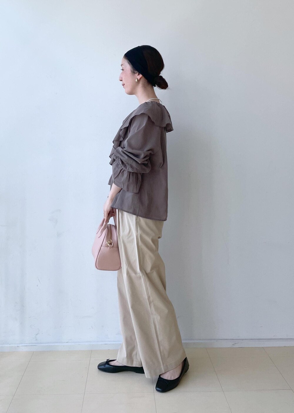 ベージュ系のチノパンツ、ピンク系のボストンバッグ、ブラック系のバレエシューズを着用したレディースの春コーディネートの4枚目の写真