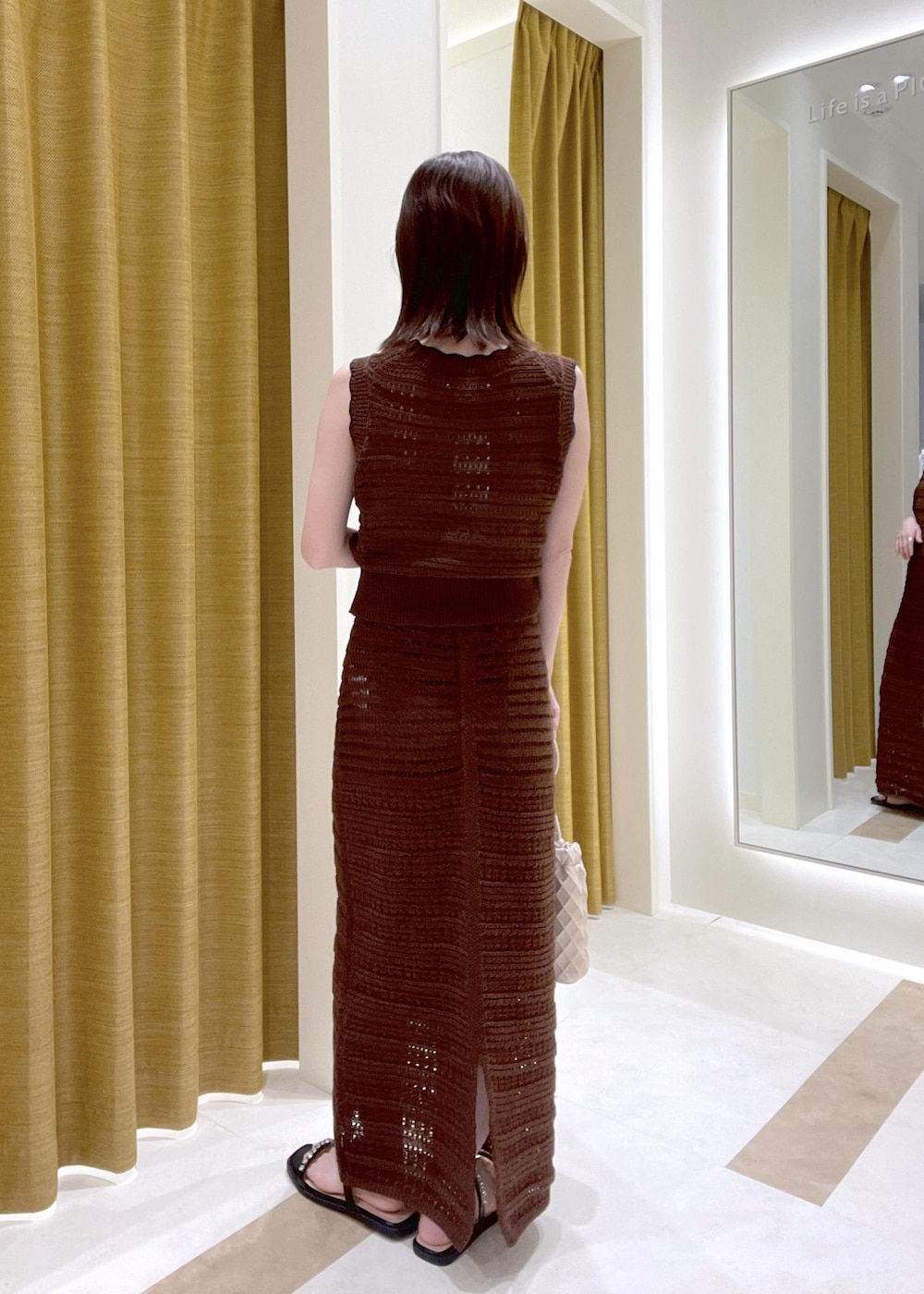 ブラック系のサンダル、ホワイト系のショルダーバッグ、ブラウン系のスカートを着用したレディースの春コーディネートの3枚目の写真