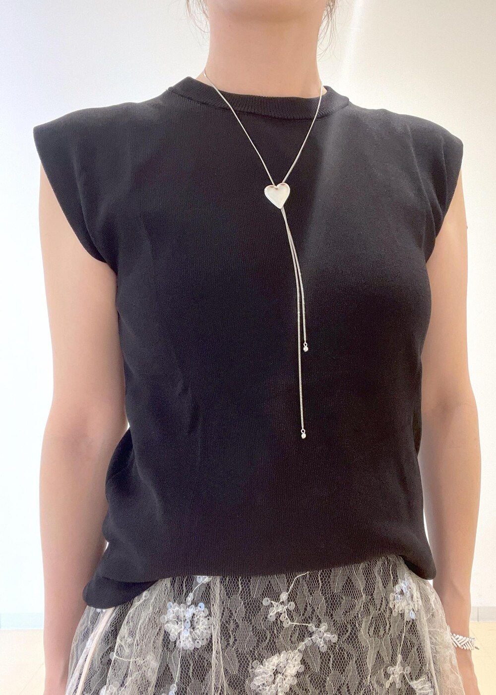 ブラック系のニット/セーター、イエロー系のショルダーバッグ、ホワイト系のスカートを着用したレディースの夏コーディネートの5枚目の写真