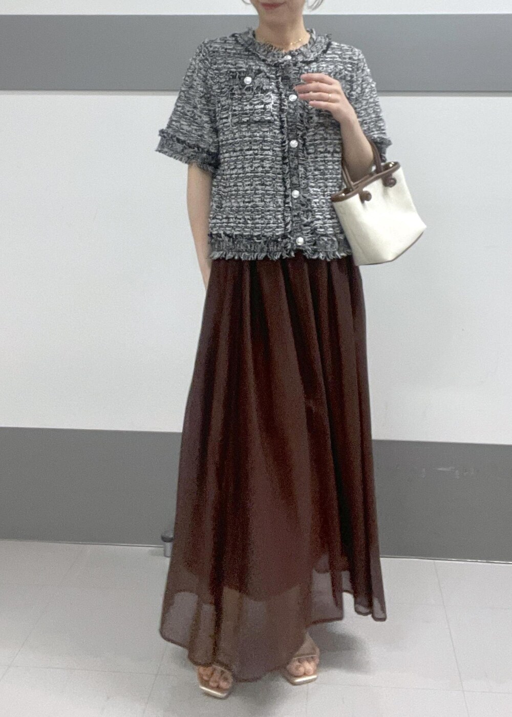 ゴールド系のサンダル、ブラウン系のトートバッグ、ブラウン系のスカートを着用したレディースの夏コーディネートの3枚目の写真