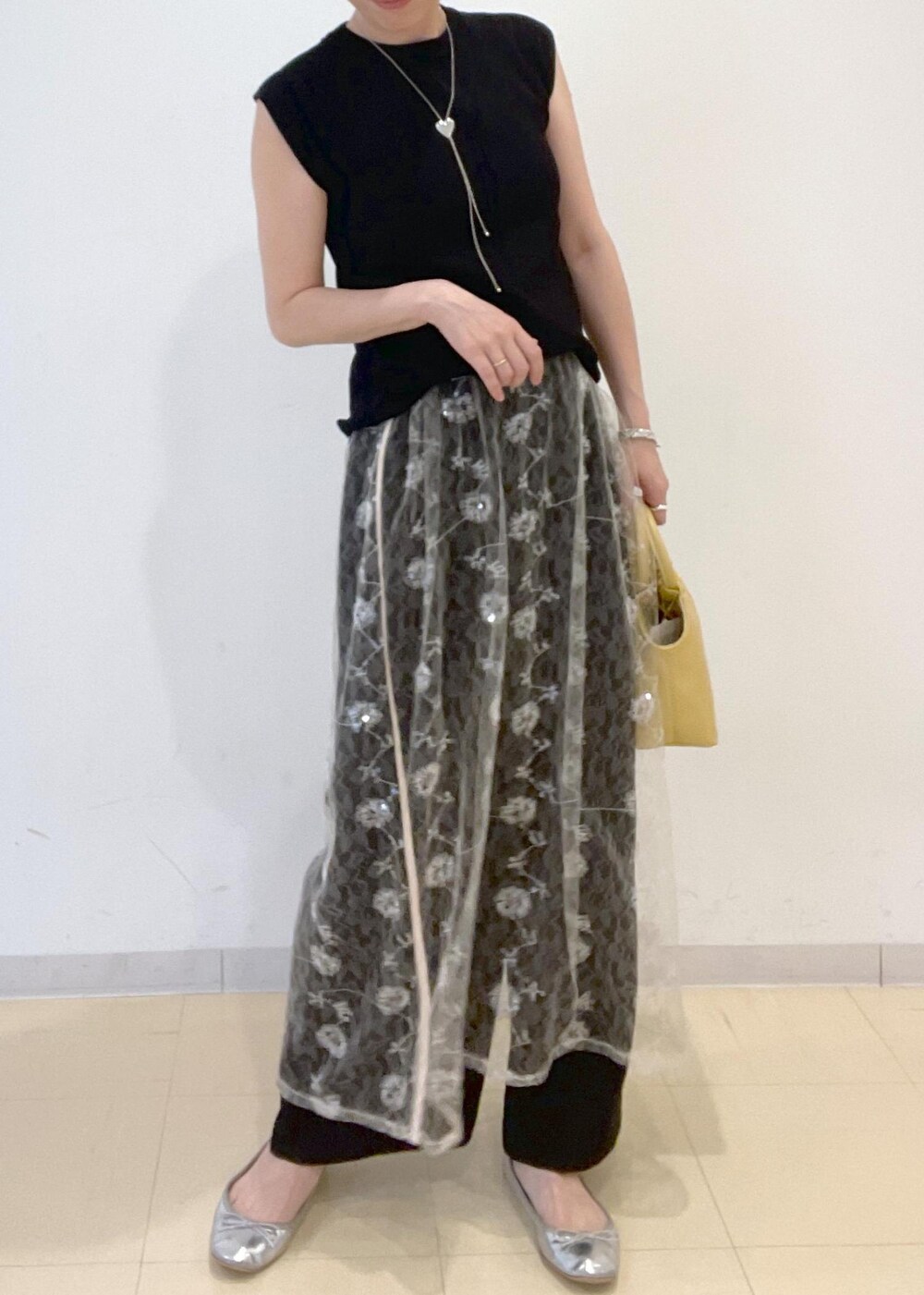 ブラック系のニット/セーター、イエロー系のショルダーバッグ、ホワイト系のスカートを着用したレディースの夏コーディネートの4枚目の写真