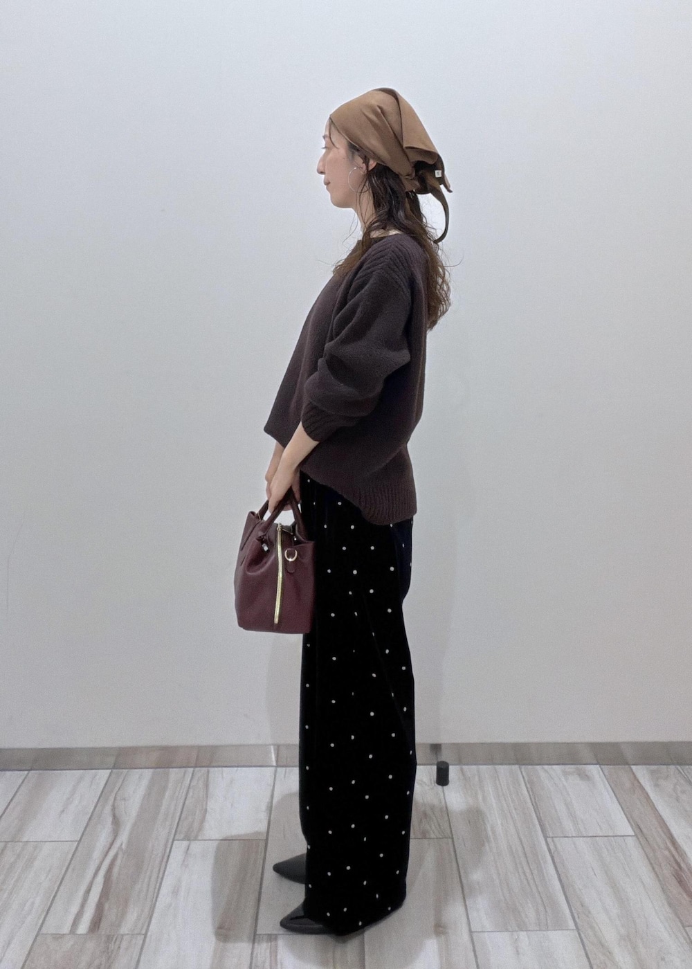 レッド系のトートバッグ、ブラック系のパンプス、ブラウン系のニット/セーターを着用したレディースの秋コーディネートの4枚目の写真