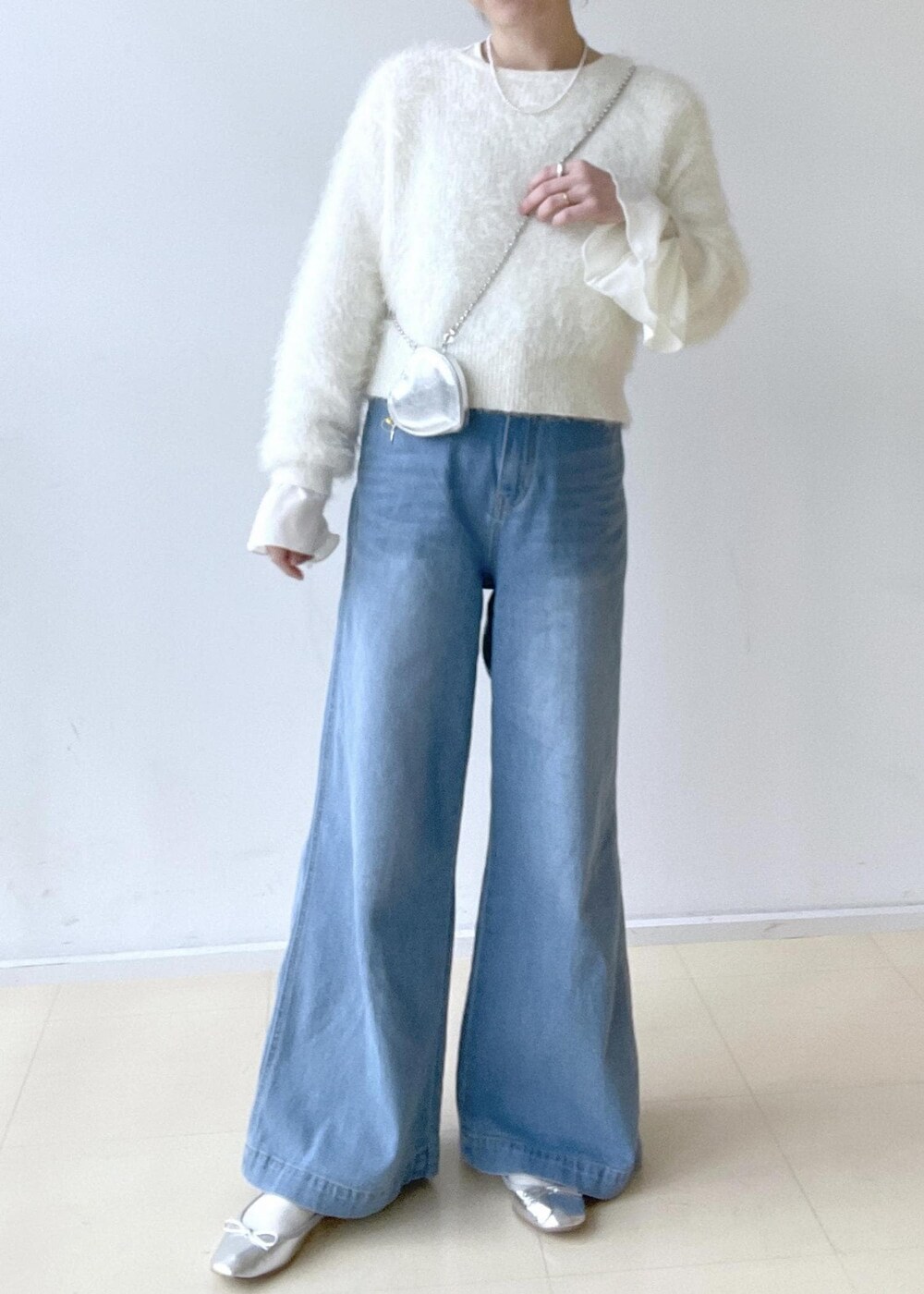ホワイト系のニット/セーター、ホワイト系のTシャツ/カットソー、ブルー系のデニムパンツを着用したレディースの冬コーディネートの3枚目の写真