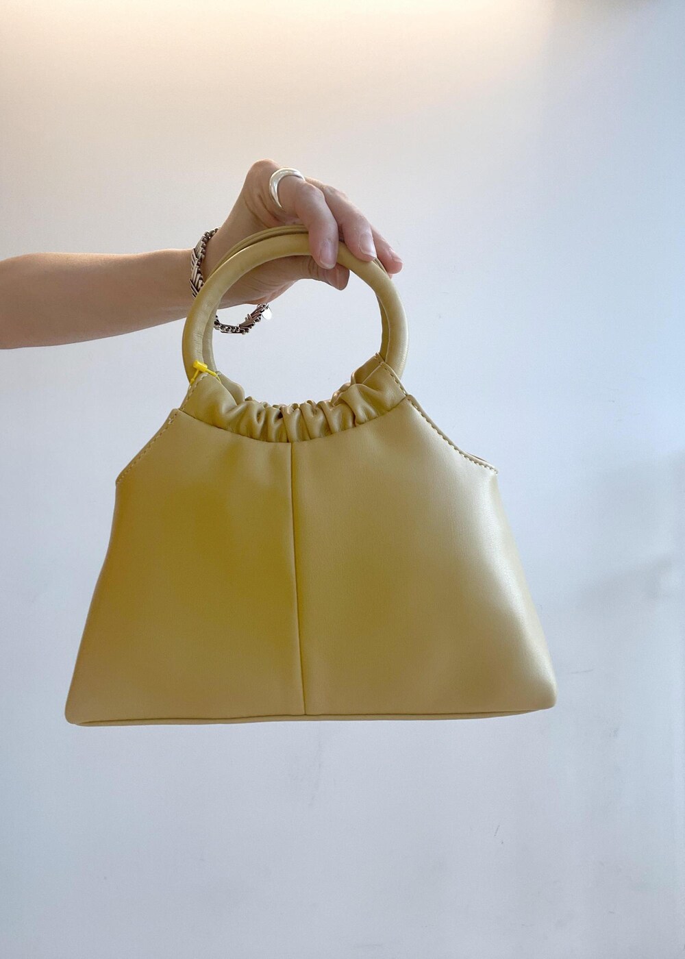 ブラック系のニット/セーター、イエロー系のショルダーバッグ、ホワイト系のスカートを着用したレディースの夏コーディネートの8枚目の写真