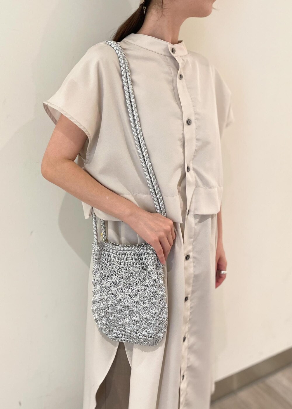 ブラック系のレインシューズ、シルバー系のショルダーバッグ、ベージュ系のシャツワンピースを着用したレディースの夏コーディネートの2枚目の写真