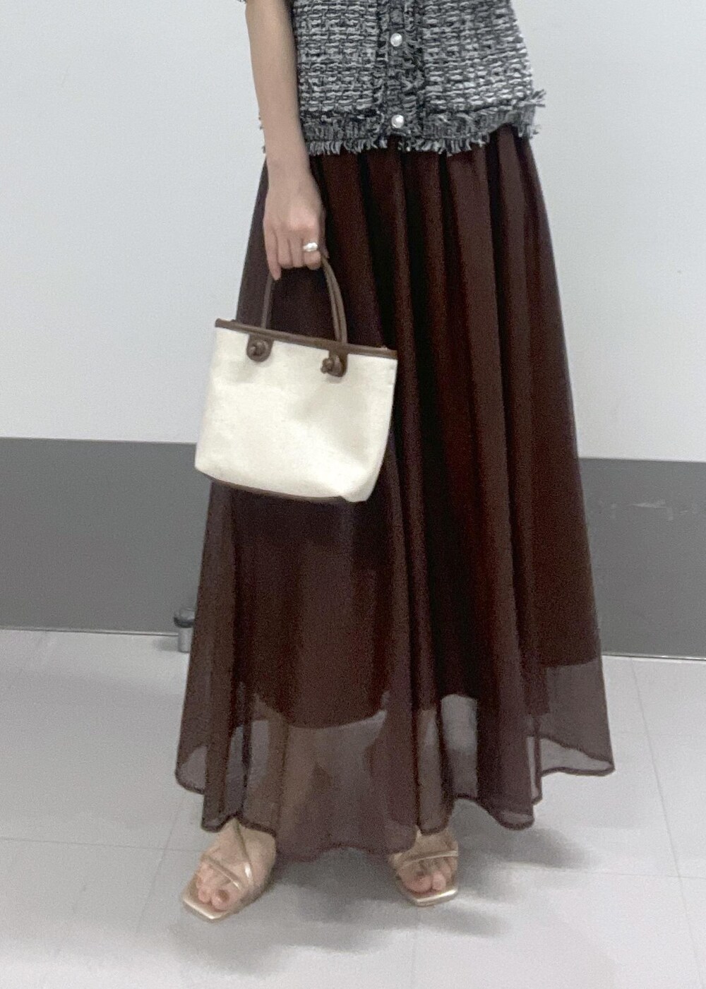 ゴールド系のサンダル、ブラウン系のトートバッグ、ブラウン系のスカートを着用したレディースの夏コーディネートの8枚目の写真