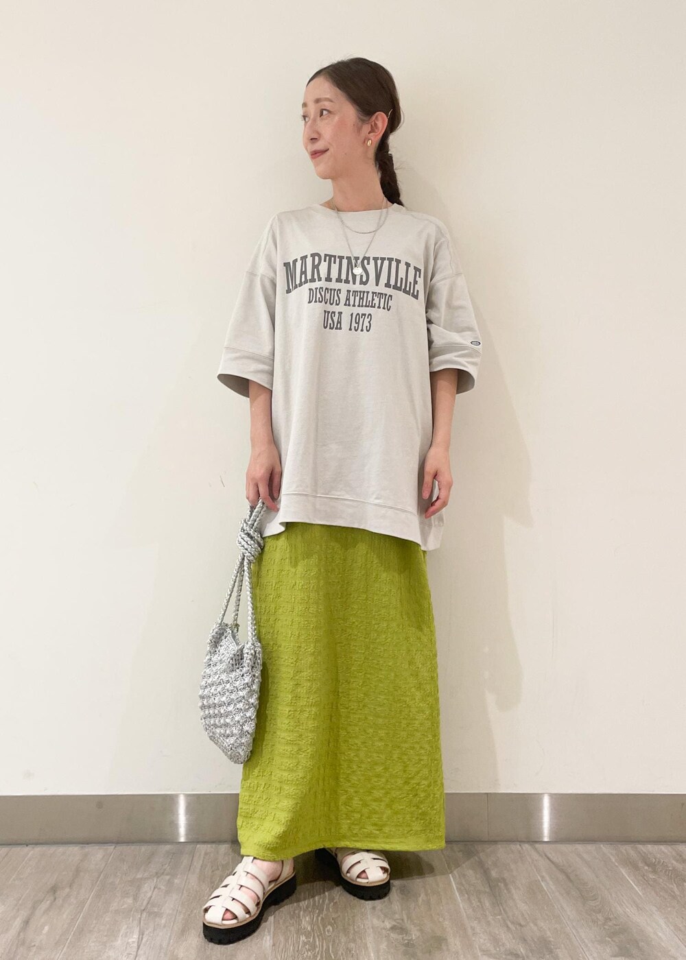 シルバー系のショルダーバッグ、ホワイト系のサンダル、グリーン系のワンピースを着用したレディースの夏コーディネートの2枚目の写真