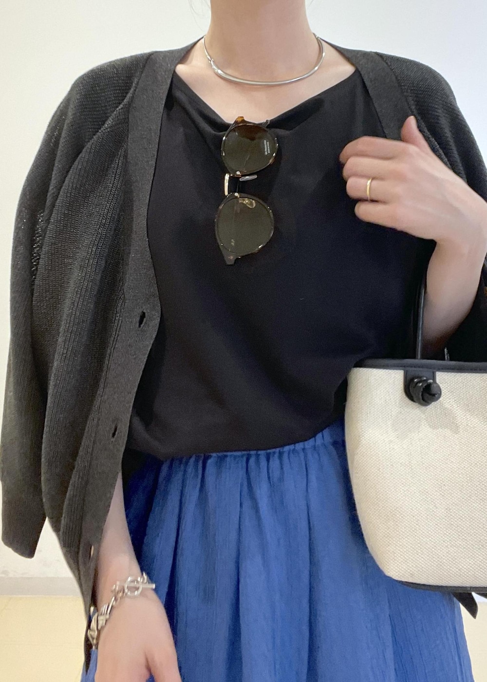 ブラック系のトートバッグ、ブルー系のスカート、グレー系のカーディガン/ボレロを着用したレディースの夏コーディネートの3枚目の写真