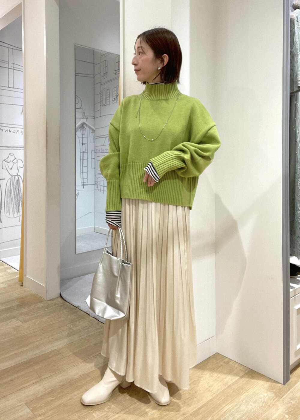 シルバー系のトートバッグ、グリーン系のニット/セーター、ホワイト系のブーツを着用したレディースの冬コーディネートの5枚目の写真