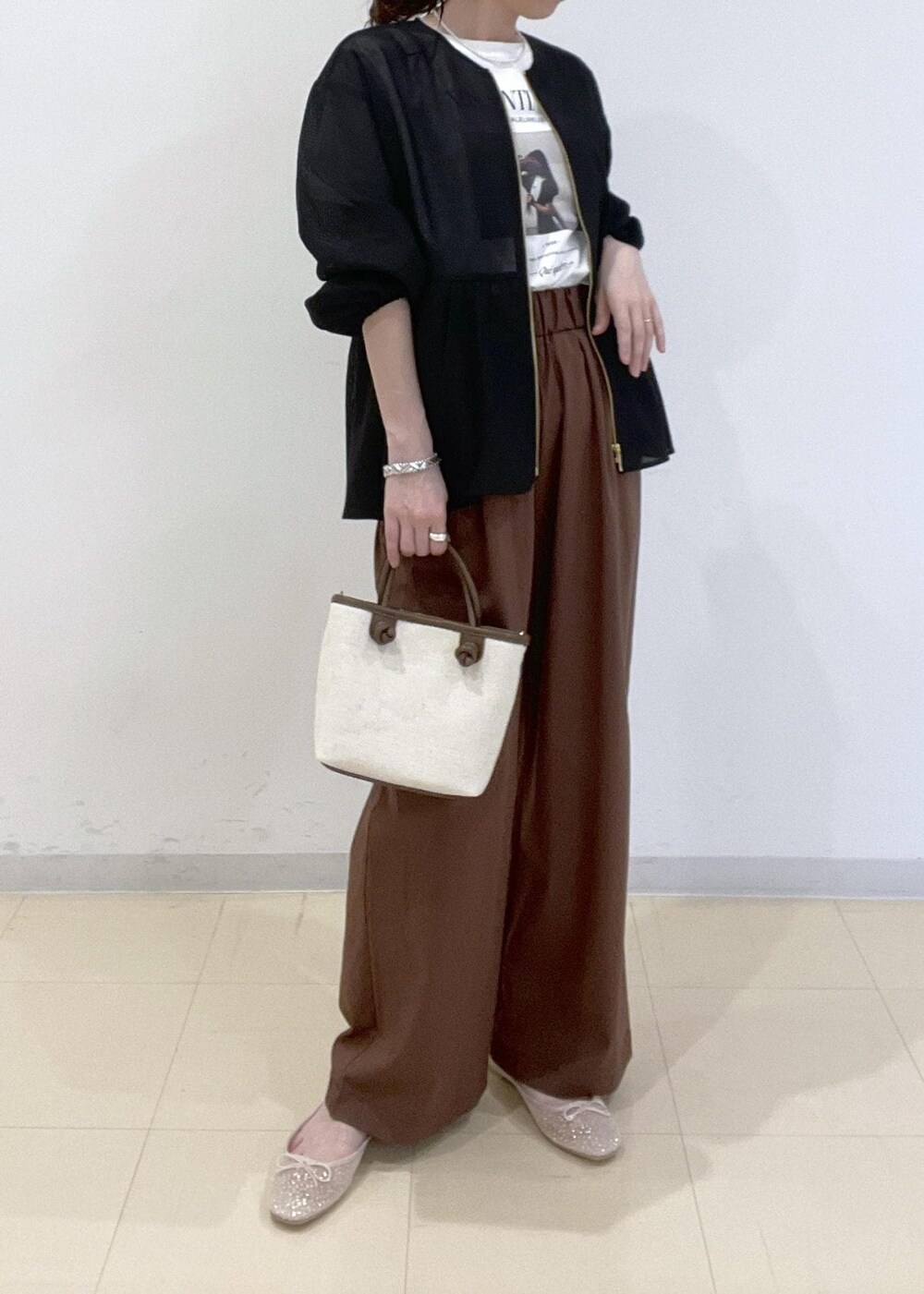ブラック系のブルゾン、ホワイト系のバレエシューズ、ブラウン系のトートバッグを着用したレディースの春コーディネートの3枚目の写真